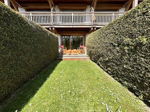 A pathway flanked by neatly trimmed hedges leading to a wooden deck with outdoor furniture. - Cozy Studio with Alcove, Ski-In Access, Near Lifts & Golf, Sleeps 4 - Megève (Megève)