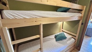 Un lit superposé à deux niveaux, chaque niveau étant équipé d’un oreiller et d’un matelas blanc.