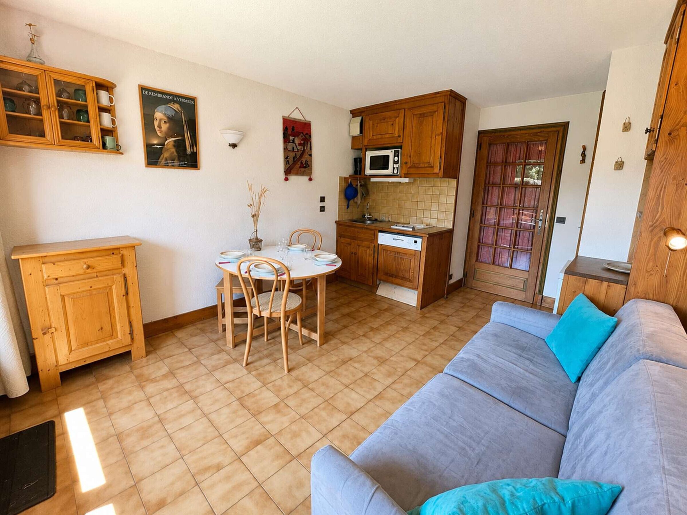 Un espacio habitable compacto con comedor, kitchenette y sofá.
