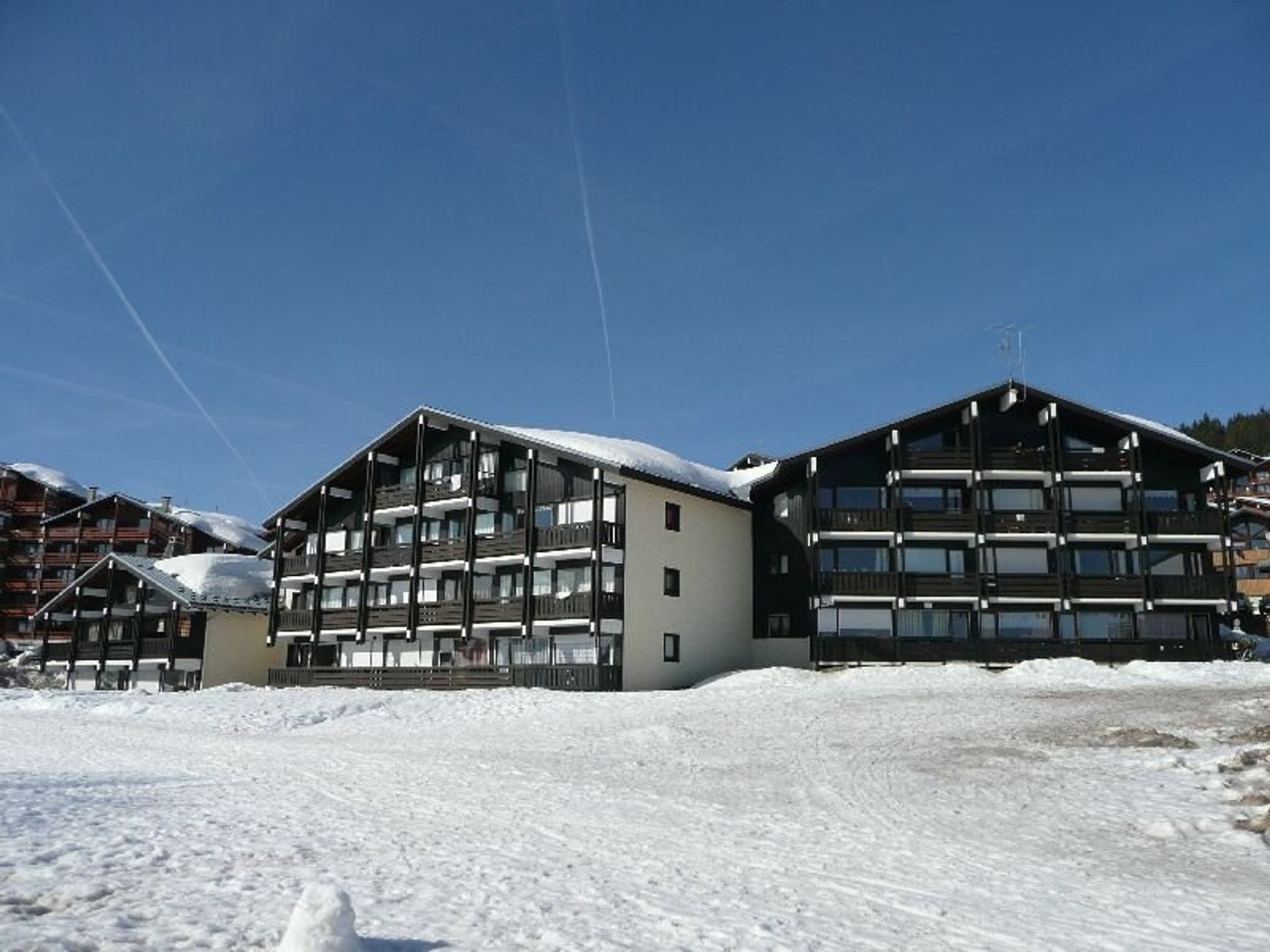 A large, multi-story building with balconies, likely a hotel or resort, surrounded by snow.