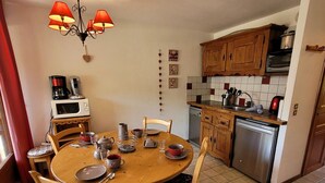 A kitchen with wooden cabinets, a microwave, a dishwasher, and a dining table with chairs.