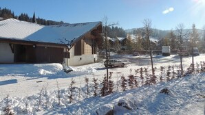 A snow-covered residential area with houses, a parked car, and a truck.