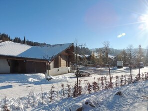Un quartier résidentiel enneigé, avec des maisons, une voiture garée et un camion.