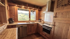 A wooden kitchen with a large window, a dishwasher, and a stove.