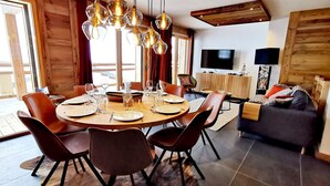 A dining area with a round table, chairs, and hanging light fixtures.