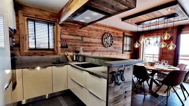 A modern kitchen with wooden accents, a central island, and a dining area with a view.