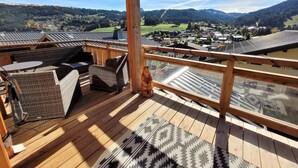 A wooden deck with wicker furniture and a view of a village.