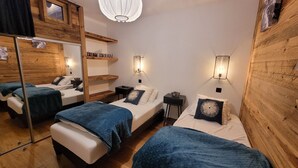 A room with three beds, wooden walls, and a hanging light fixture.