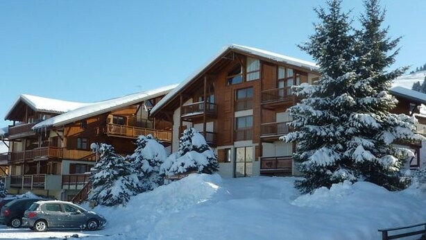A wooden lodge with multiple balconies and a snow-covered landscape.