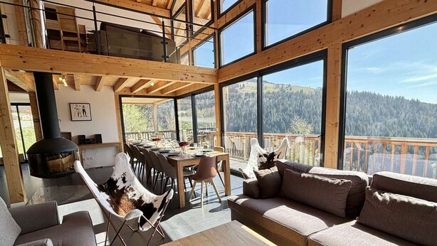 Un vaste espace de vie doté d’une grande table en bois, de sièges confortables et d’une cheminée.
