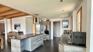 Une cuisine moderne dotée d’un îlot central, d’appareils électroménagers intégrés et d’un plafond en bois.