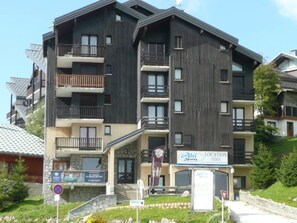 Un hôtel à plusieurs étages doté de balcons, d’un panneau indiquant l’emplacement des pistes de ski et d’un panneau interdisant le stationnement.