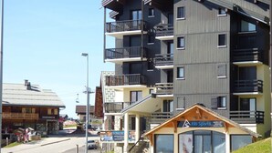 Un immeuble à plusieurs étages doté de balcons, un magasin d’articles de ski et un restaurant.
