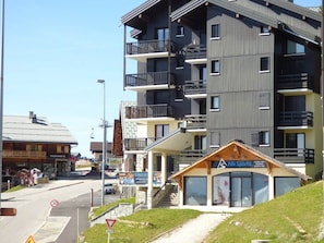 A multi-story building with balconies, a ski resort sign, and a small wooden structure labeled 'Alti Sports'. - Studio cabin Les Saisies, 4 people, central with balcony (Les Saisies)