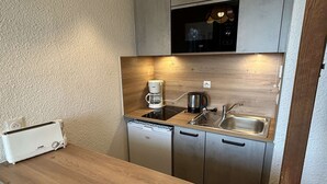 Une petite cuisine équipée d’un grille-pain, d’une machine à café, d’un four à micro-ondes et d’un évier.