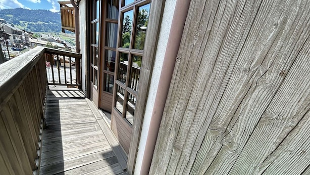 A wooden deck with a view of a town and mountains in the background.