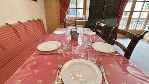 A dining table set with plates, glasses, and cutlery, surrounded by wooden chairs and a bench.