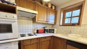 A kitchen with wooden cabinets, a white stove, a microwave, and a coffee maker.