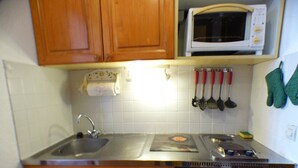 A kitchen with wooden cabinets, a microwave, a stove, and a dishwasher. - Studio cabin Les Saisies 4 pers, near slopes (Les Saisies)