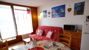 A cozy room with a red patterned sofa, a wooden cabinet, and a table with a placemat. - Studio cabin Les Saisies 4 pers, near slopes (Les Saisies)