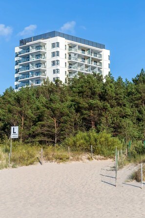 Moderni, useita kerroksia sisältävä rakennus, jossa on parvekkeet. Se on ympäröity tiheällä mäntymetsällä ja sen lähellä on hiekkaranta.