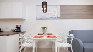 A modern kitchen with white cabinets, a wooden countertop, and a dining area with a table set for four.