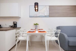 Una cocina moderna con armarios blancos, encimera de madera y comedor con mesa dispuesta para cuatro.