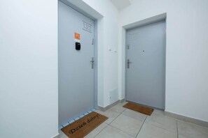 A hallway with two doors, each marked with a number. There are doormats on the floor and a small sign on the wall.