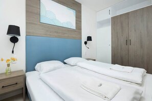Ein Hotelzimmer mit Bett, Nachttischen, Nachttischlampen, Spiegel und Kleiderschrank.