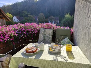 A table set with a plate of food, a glass pitcher, and a vase with flowers. - Limerhof Vacation Cottage - Vacation Cottage (Waischenfeld)