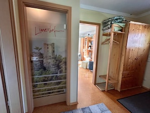 Ein Zimmer mit einem Holzschrank, einer Tür mit Wandgemälde im Schlossstil, einer Holzkommode mit gefalteter Kleidung und einem Teppichboden.