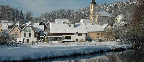A town with buildings, a church with a tower, and a frozen river.