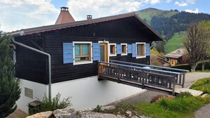 A chalet with a wooden deck and a view of a mountainous landscape. - Cozy chalet with fireplace and parking, for 8 people (Les Gets)