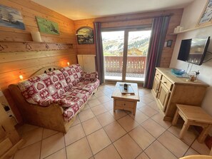 A cozy room with a wooden sofa, a small table, and a TV.