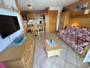 Un salon chaleureux avec un canapé en bois, une table basse et un téléviseur.