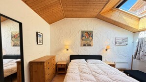A bedroom with a wooden ceiling, a bed, a dresser, and a skylight. - Cozy apartment in Les Gets with balcony and parking (Les Gets)