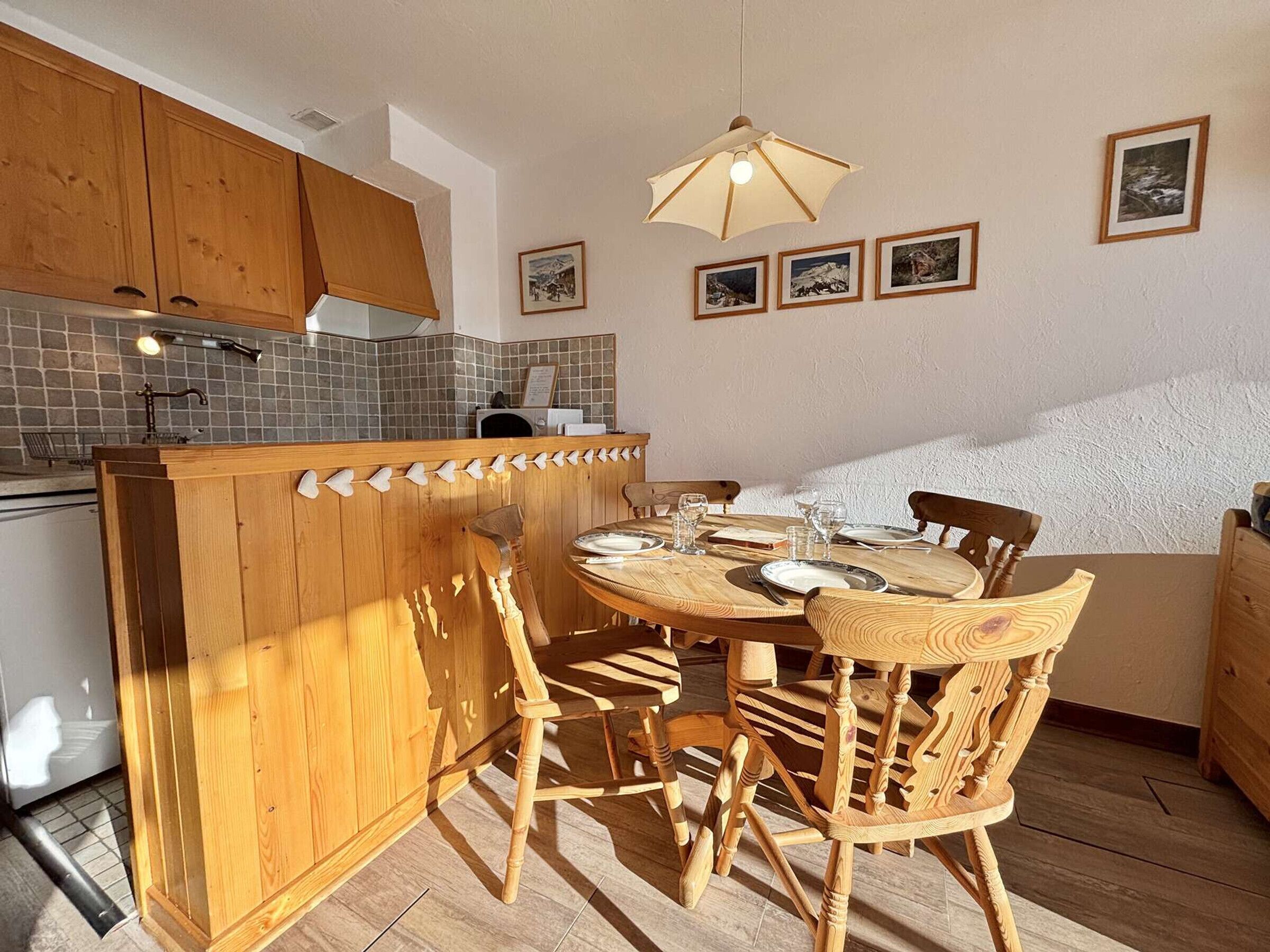 A kitchen with wooden cabinets, a tiled backsplash, a wooden island, and a dining area with wooden chairs and a table.