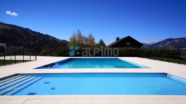 A rectangular swimming pool with a tiled deck, surrounded by a fence, and set against a backdrop of mountains and a clear sky. - 2-room apartment, pets allowed, parking in Notre-Dame-de-Bellecombe (Notre-Dame-de-Bellecombe)