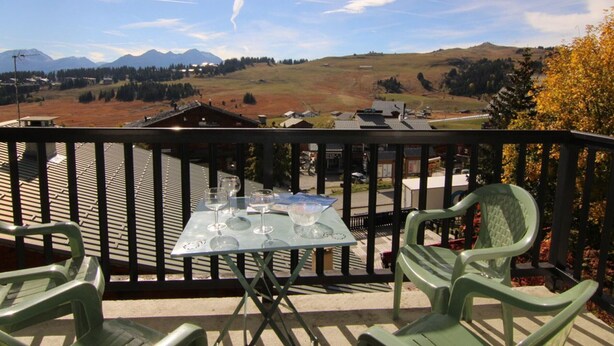 A balcony with a table set for two, overlooking a mountainous landscape. - 2-Room Apt - 5 people, Les Saisies, Pets allowed (Les Saisies)