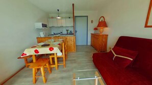 A compact living space with a dining area, kitchen, and a red sofa. - 2-Room Apt - 5 people, Les Saisies, Pets allowed (Les Saisies)