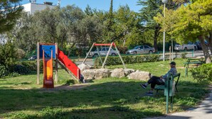 Ein Park mit Spielgeräten, einer Bank und einem gepflasterten Weg.
