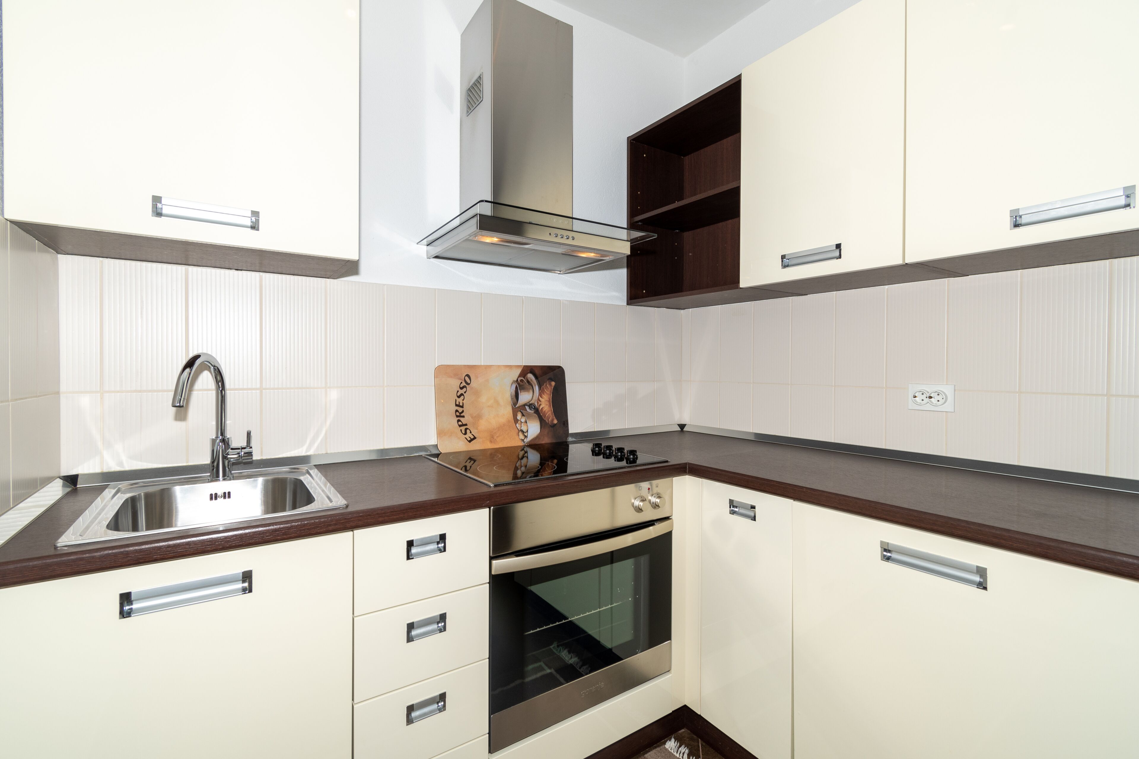 A modern kitchen with a stainless steel sink, a built-in oven, and a range hood.