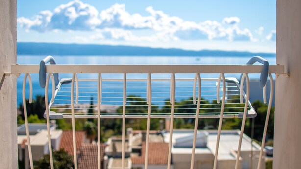 Ein Balkon mit Metallgeländer und Blick auf ein Gewässer sowie entfernte Berge.