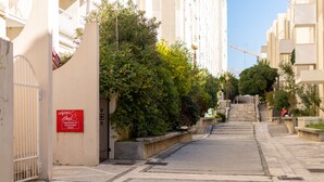 Eine schmale Stadtstraße mit einem befestigten Eingang, einem roten Schild und einer Treppe, die zu einem Gebäude hinaufführt.