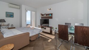 Ein modernes Hotelzimmer mit Bett, Fernseher, Schreibtisch mit Stuhl und einem Balkon mit Blick.