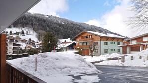 A snow-covered street with houses and a mountain in the background. - Renovated apartment for 4, near center, parking (Les Gets)
