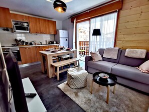 A compact living space with a kitchenette, a dining area, and a seating area with a sofa and a small table. - Renovated apartment for 4, near center, parking (Les Gets)