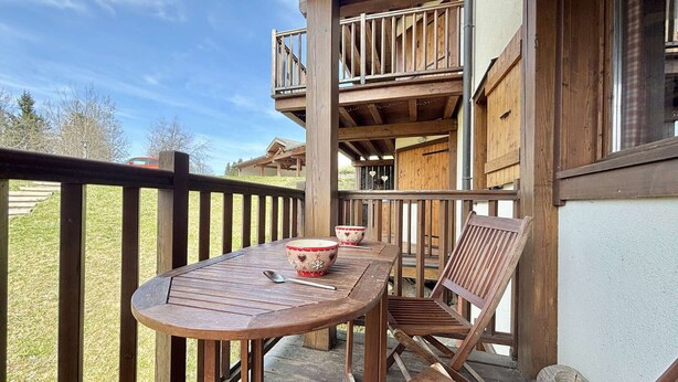 Eine Holzdar Terrasse mit Tisch, Stühlen, Geländer und Blick auf die umliegende Landschaft.