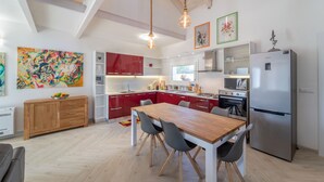 Eine moderne Küche mit einem Holzespeisetisch, roten Schränken und einem Edelstahlkühlschrank.