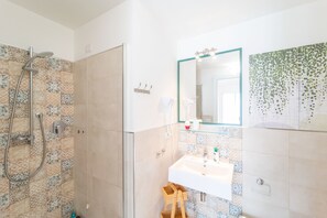 A bathroom with a shower, sink, and mirror.
